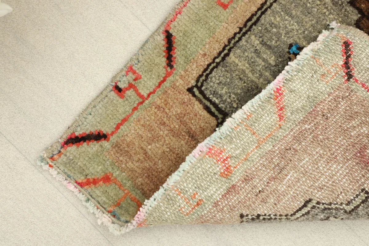 Angled view of the rug with one end folded, showcasing the wool pile texture and colors from the side.