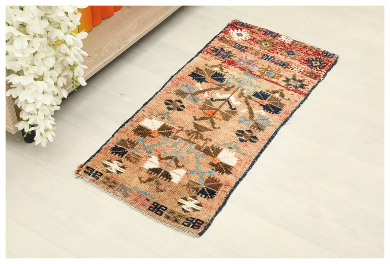 Full overhead view of the beige tribal geometric doormat on a white background.