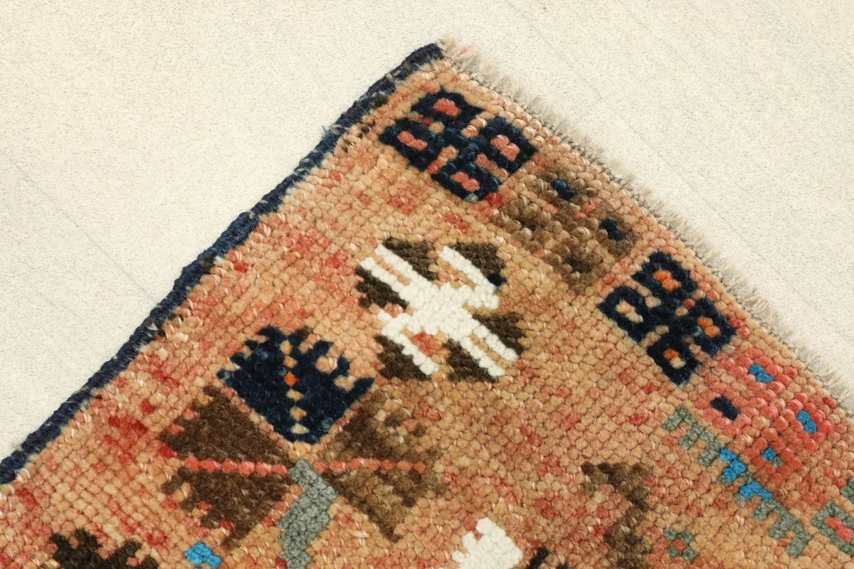 Corner detail showing the navy blue edge and part of the beige field with small motifs.