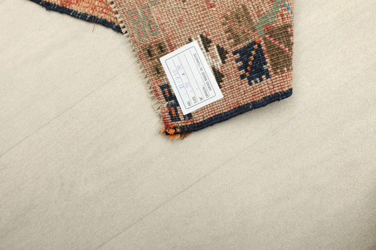Close-up of the rug's back, showing the hand-knotted cotton foundation and a product label.
