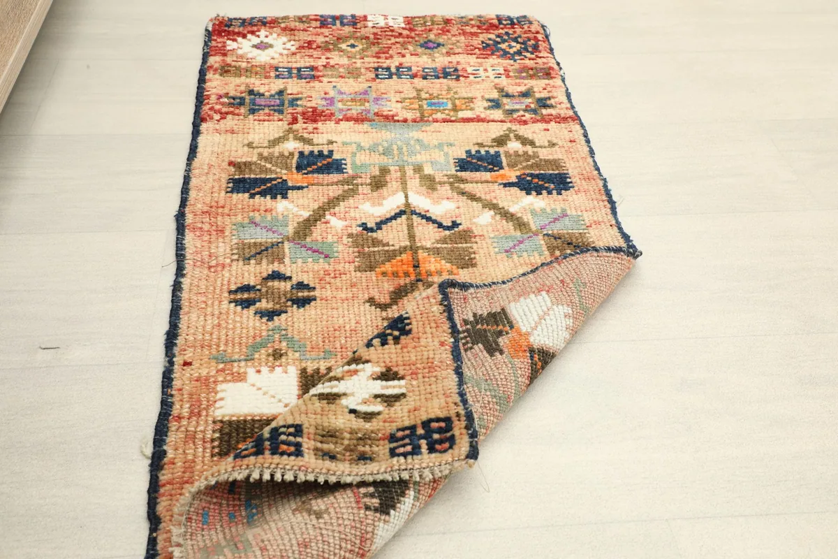 The doormat partially folded, revealing the reverse side of the hand-knotted construction.