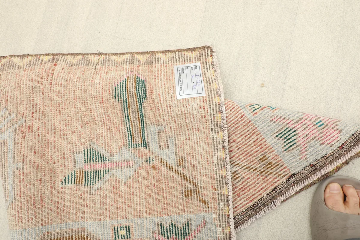 Overhead view of the rug laid out on a light floor next to a wooden shelf, showing scale.