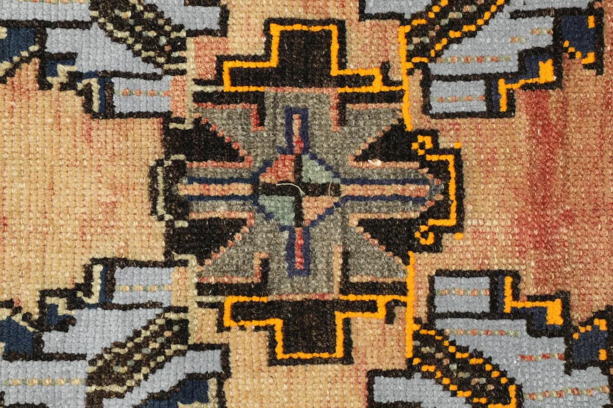 Close-up of a central geometric motif in gray, black, and yellow on the rug.