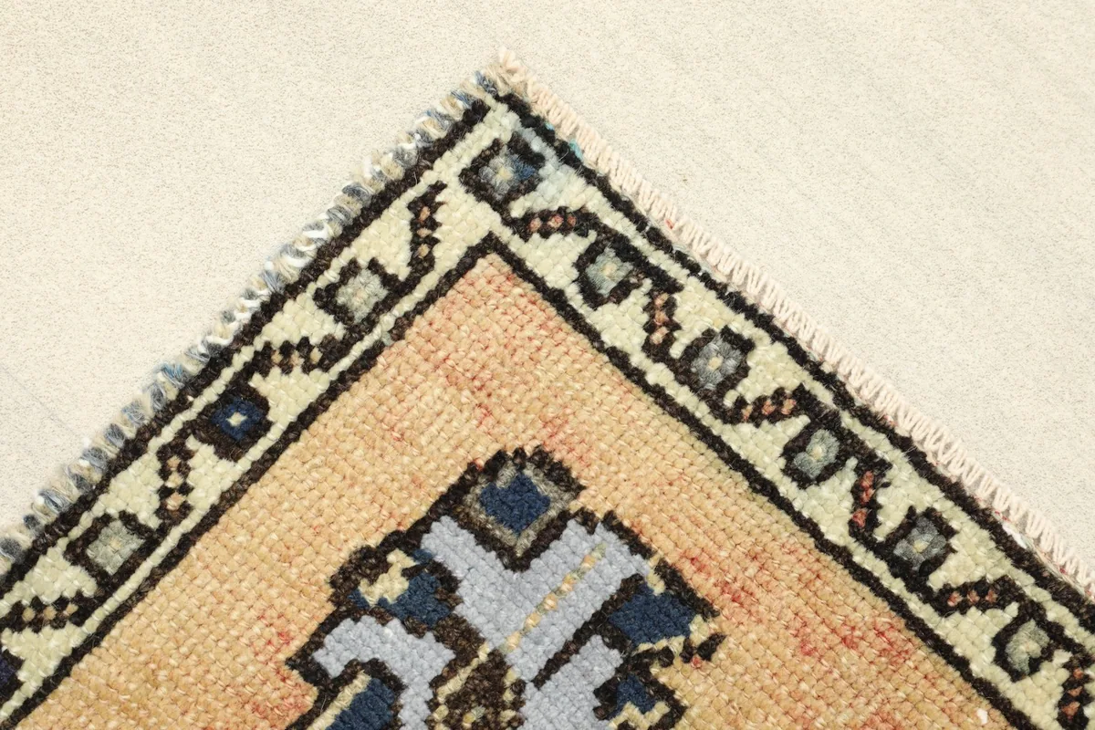 Detail of the corner showing the beige border with black and blue patterns.