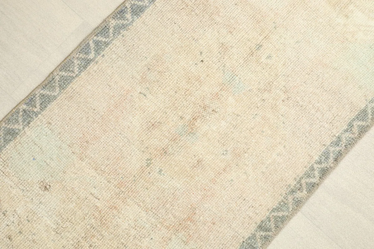 Close-up view of the ivory field and blue geometric border, highlighting the vintage texture and subtle color variations.