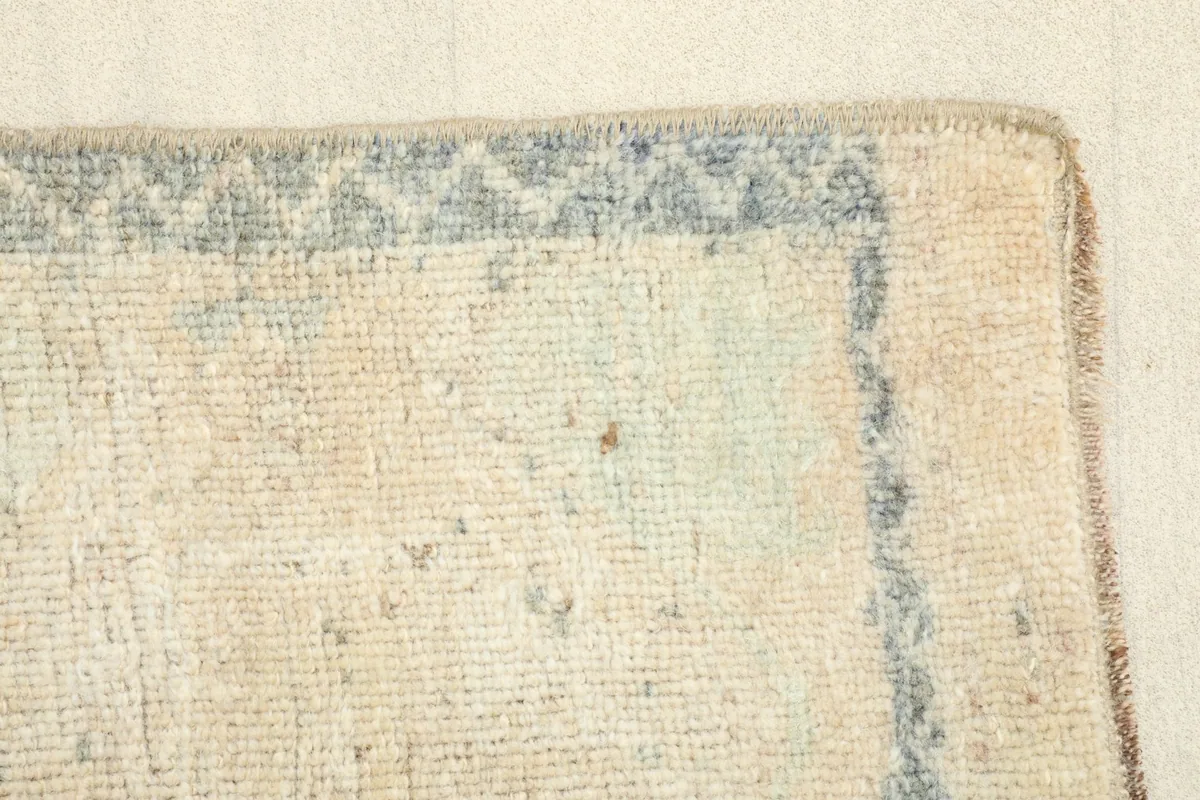 Close view of the rug's edge, showing the subtle wear and the intricate pattern of the border.