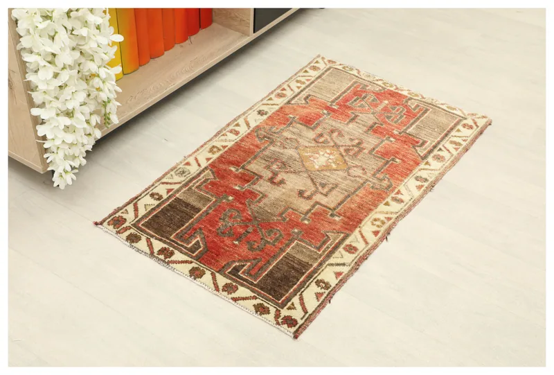 Full top view of the vintage Anatolian rug with red, beige, and brown geometric patterns on a white background
