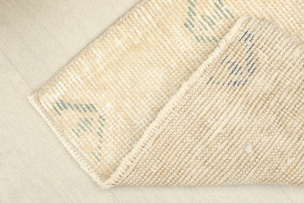 A folded section of the rug, revealing the wool pile and cotton foundation from the side.