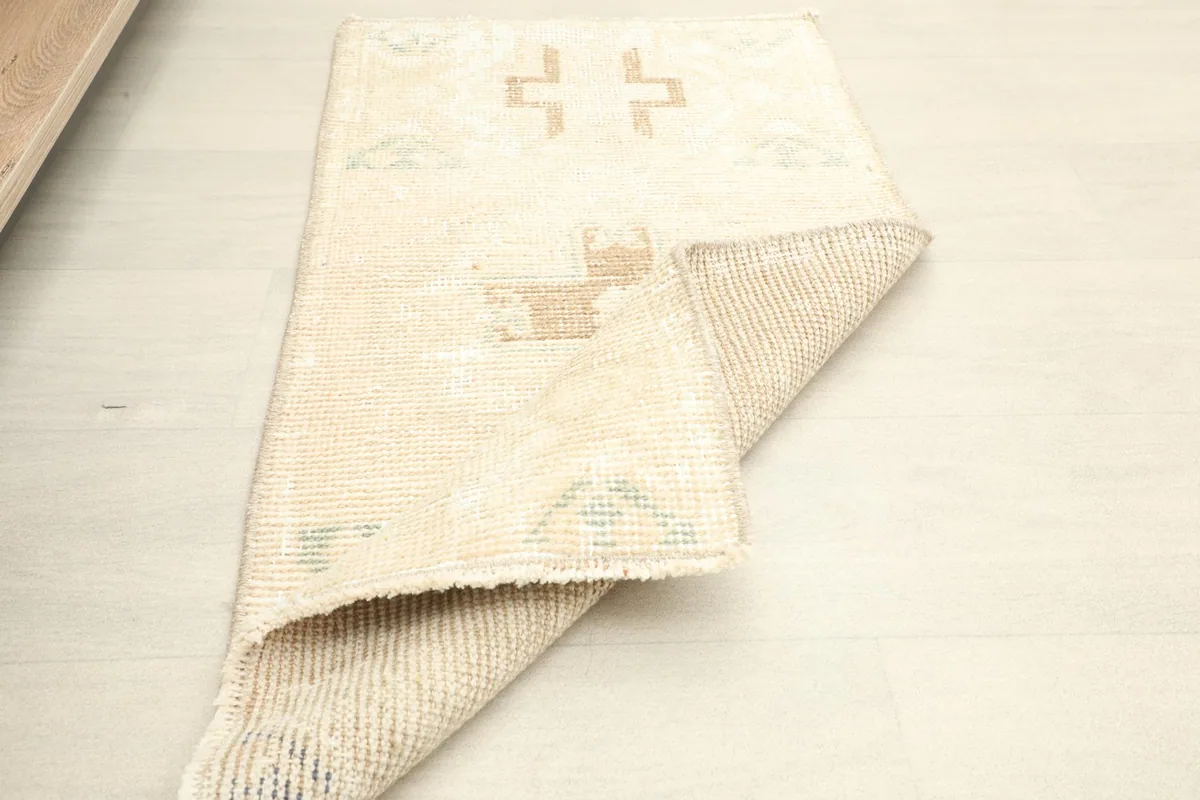 The rug partially folded, showing the back of the hand-knotted construction and the overall design.