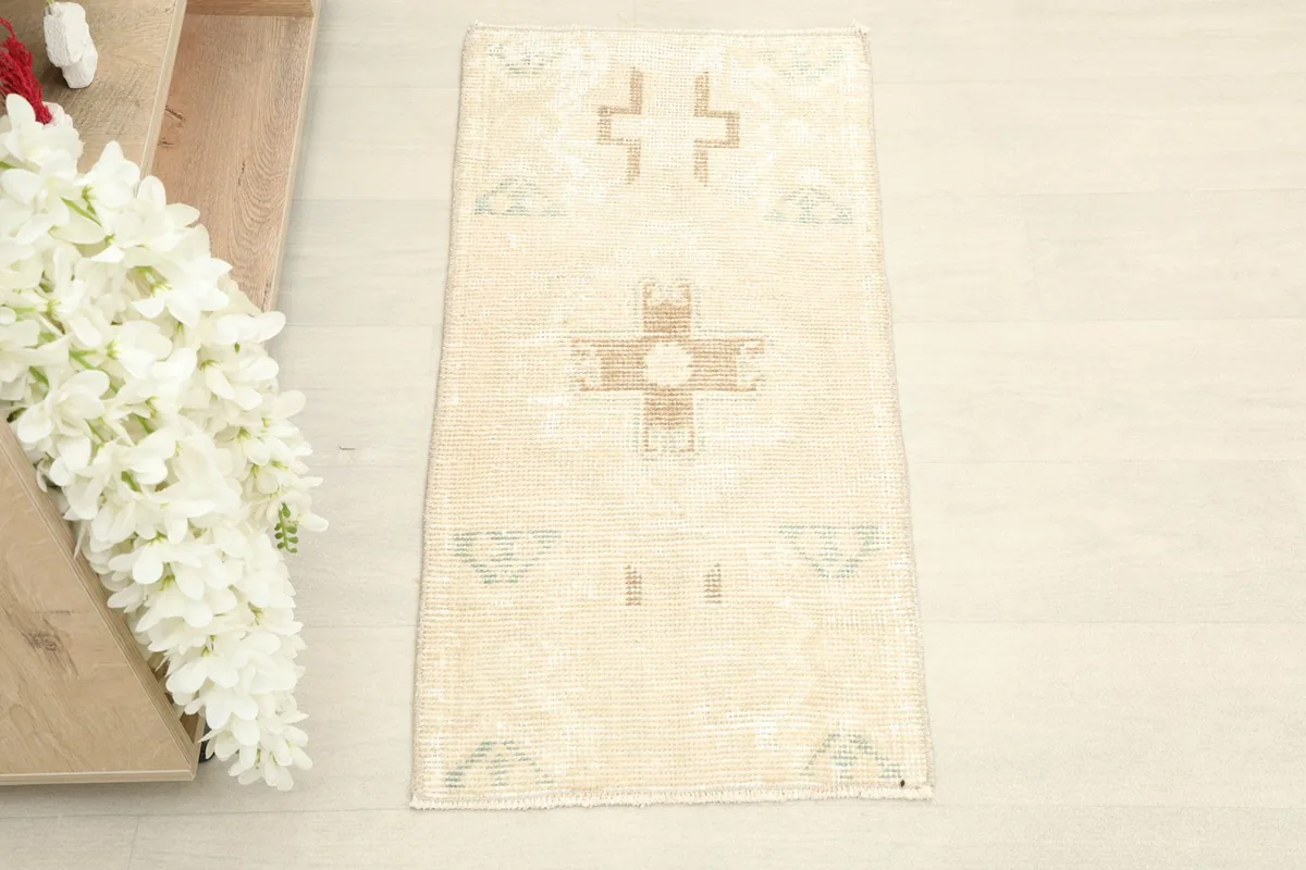 Top-down view of the small hand-knotted rug, highlighting its ivory field and tan geometric motifs.