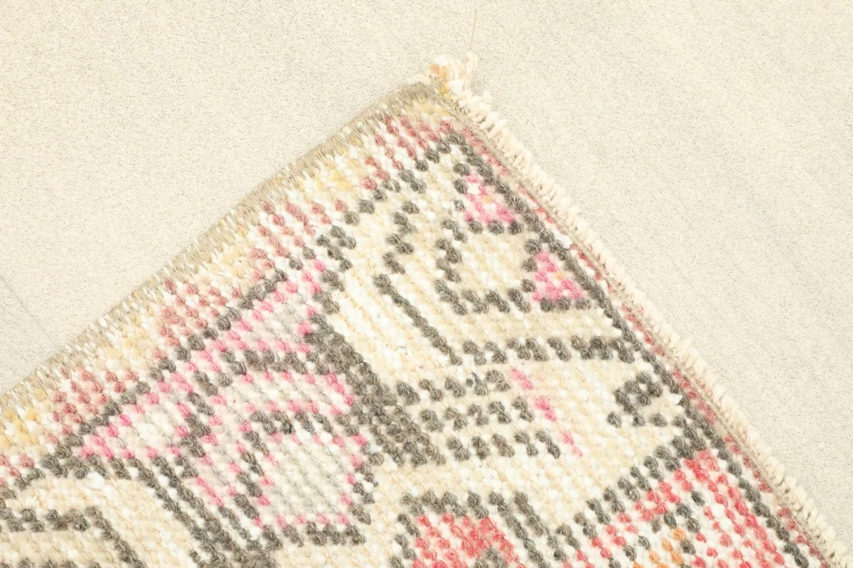 Angled view of a corner of the rug, showing the geometric border design and the natural wear on the pile.