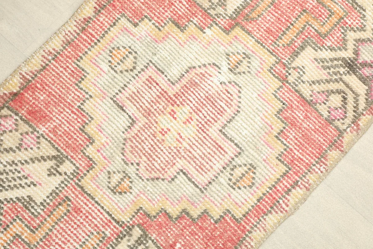 Close-up detail of the central rose medallion and surrounding geometric patterns in ivory, beige, and gray.
