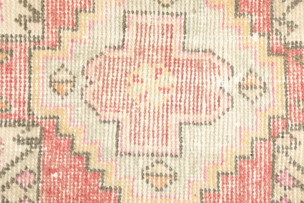 Tight detail of the hand-knotted wool pile, highlighting the texture and color variations in the rose and ivory design.