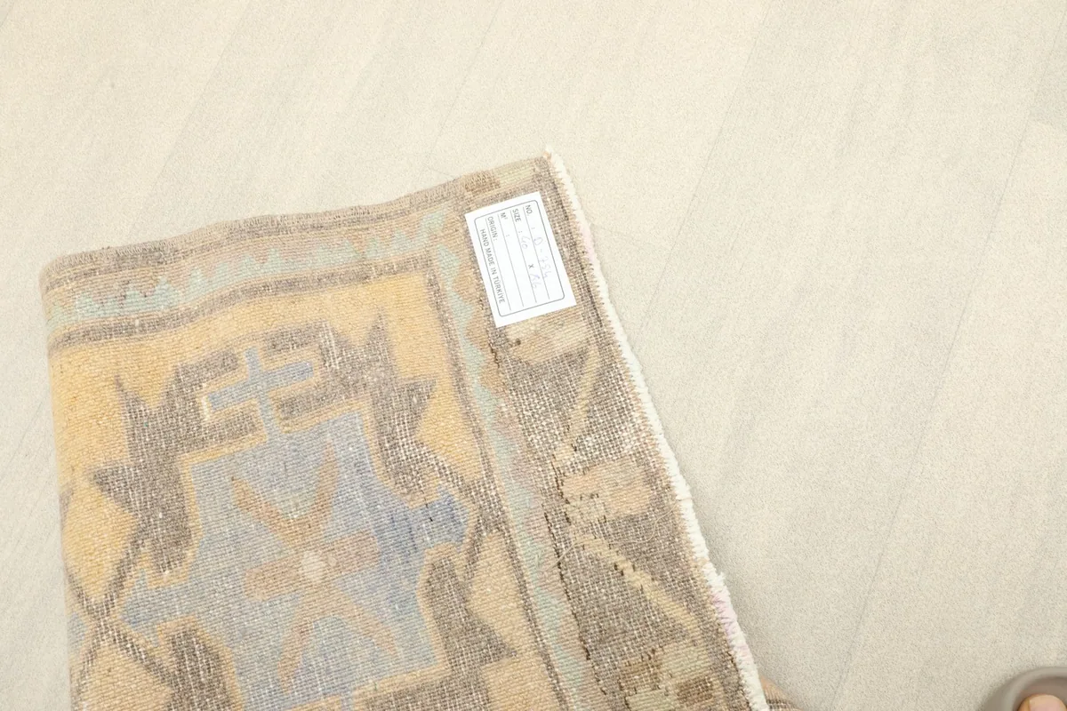 Back of the rug with its tag, showing the hand-knotted foundation