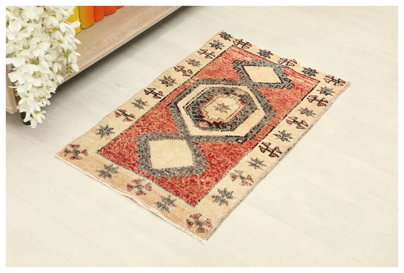 Full top view of the 1'8" x 2'9" vintage Anatolian rug with red field and beige border on a white background