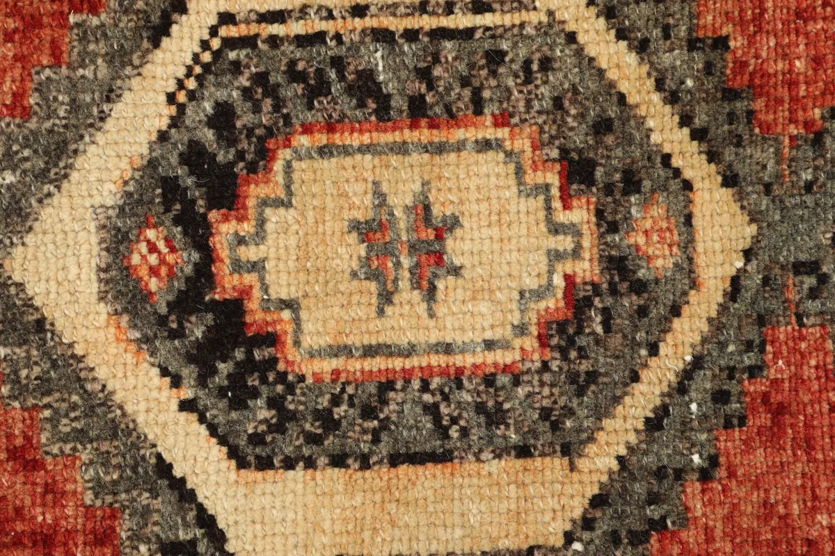 Close-up detail of the central geometric motif with beige, black, gray, and red colors