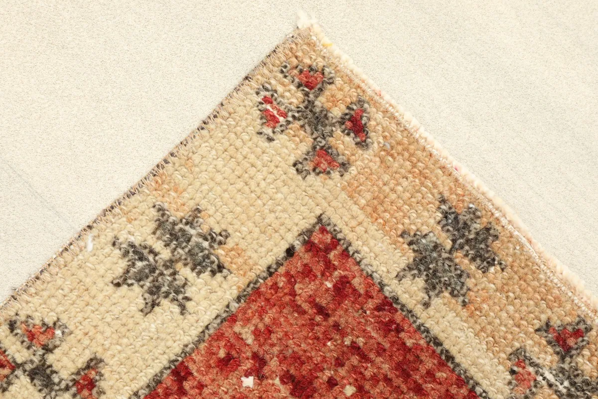 Corner detail showing the beige border with black and red tribal motifs and the red field