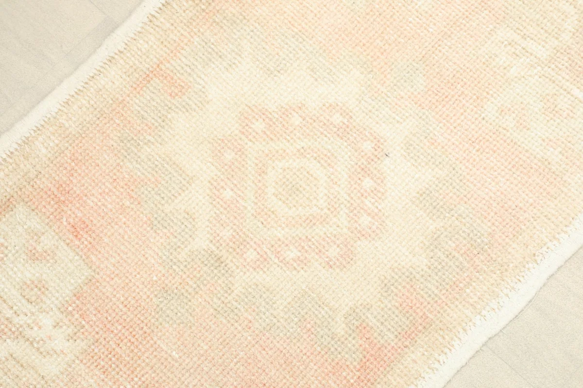 Close-up of the faded rose and cream geometric patterns, showing the central motif.
