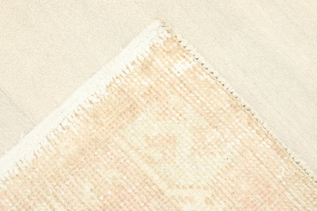 Corner flipped to show the back of the hand-knotted rug and its cotton foundation.