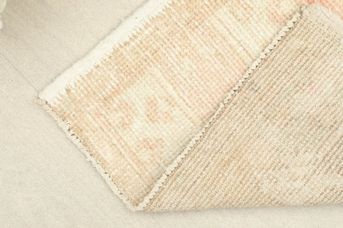 Angle view of the rug's corner folded back, revealing the reverse side and hand-knotting.