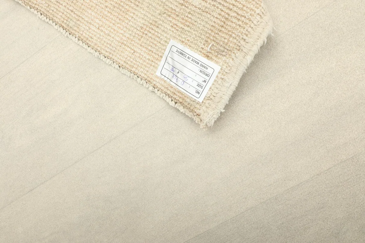 Close-up of the back of the rug with its product label, indicating origin and material.