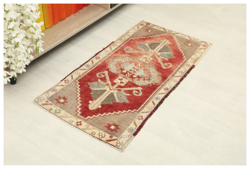 Full overhead view of the 2x3 red tribal vintage rug on a white floor