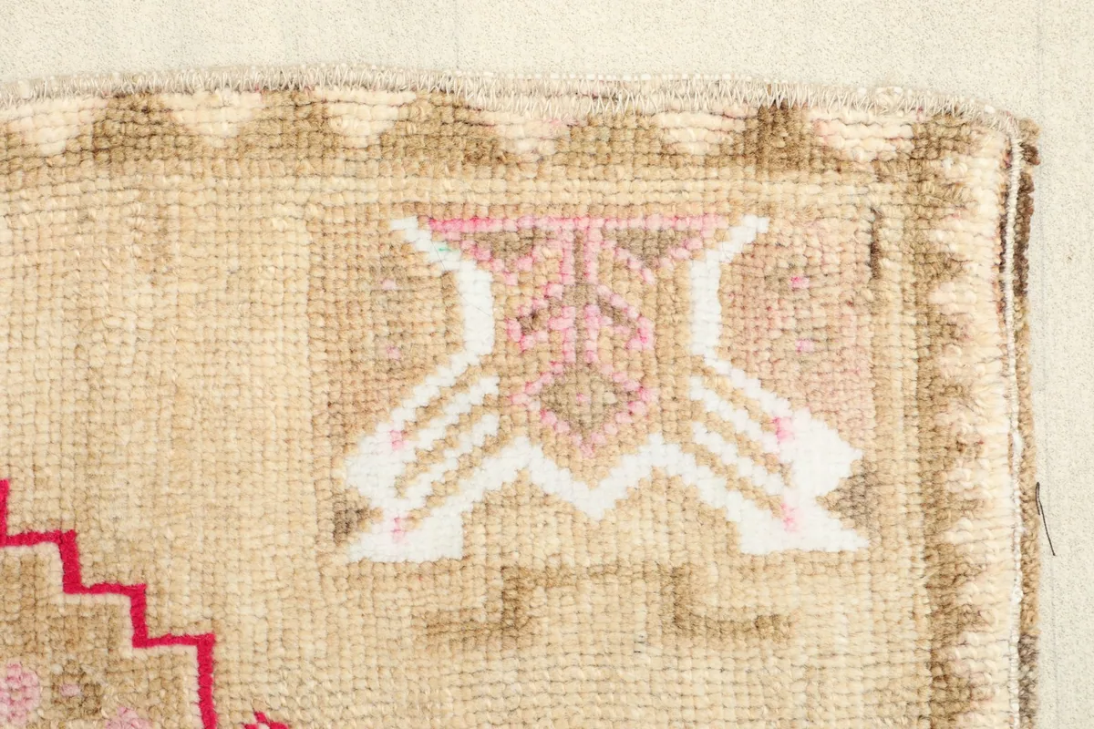 Close-up of a side geometric motif in pink and tan on the rug's field