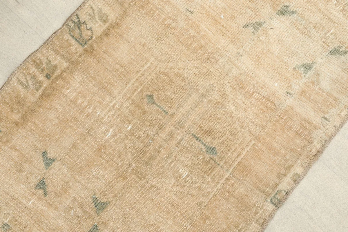 Close-up detail of the hand-knotted wool pile and faded geometric patterns in blue and green.