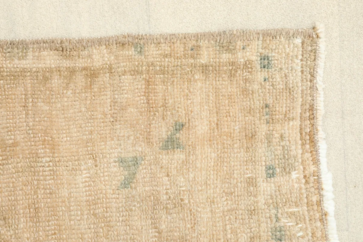 Edge detail of the rug, highlighting the natural wear and hand-finished sides.