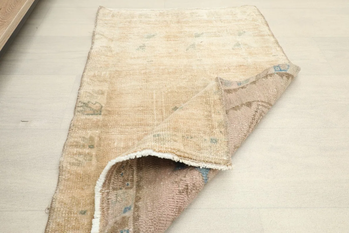 Partially folded rug displaying the reverse side's construction and muted colors.
