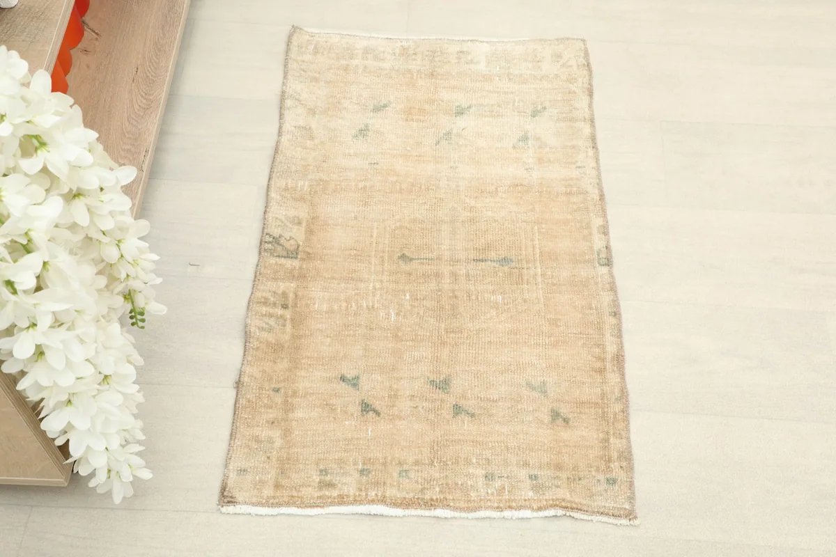 Overhead view of the small beige rug, showcasing its full design and color variation.