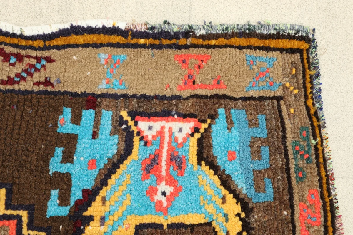 Close-up of a tribal motif in blue and yellow, with a red outline, near the rug's edge
