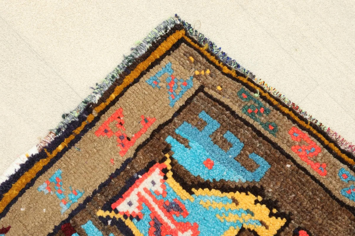Corner detail showing the beige border with geometric patterns and the rug's natural edge