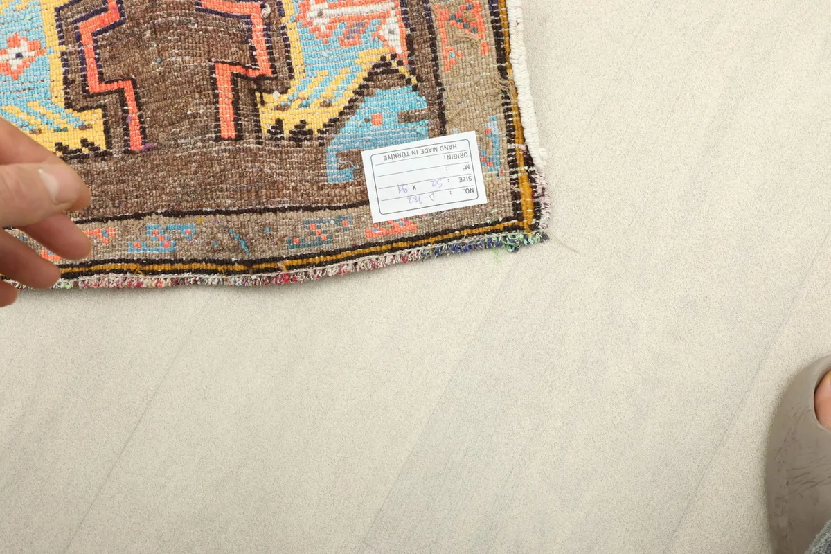 Hand pointing to the care label attached to the corner of the professionally cleaned rug