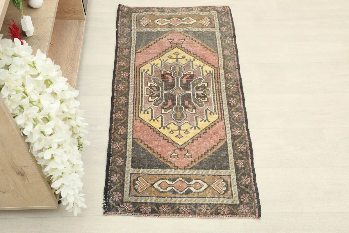 Direct overhead shot of the hand-knotted rug, highlighting its gray, pink, and yellow colors.