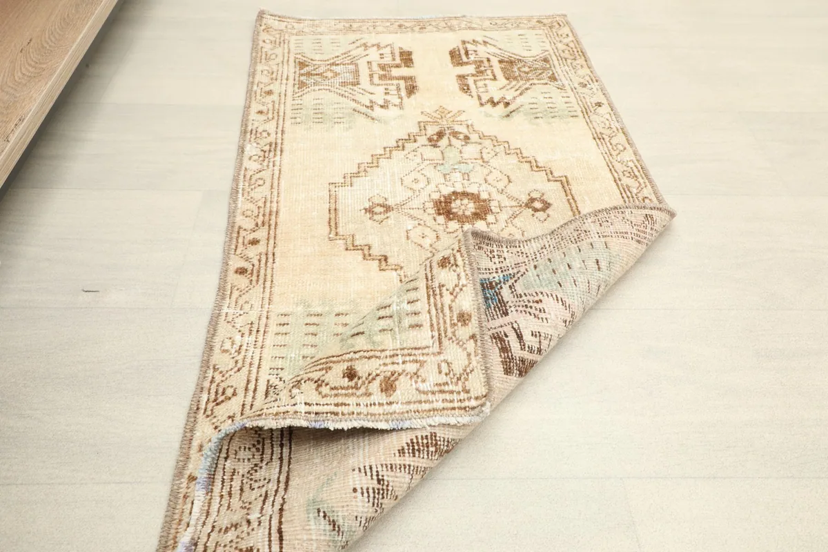 Rug partially folded, revealing the underside and the overall low pile of the vintage piece.