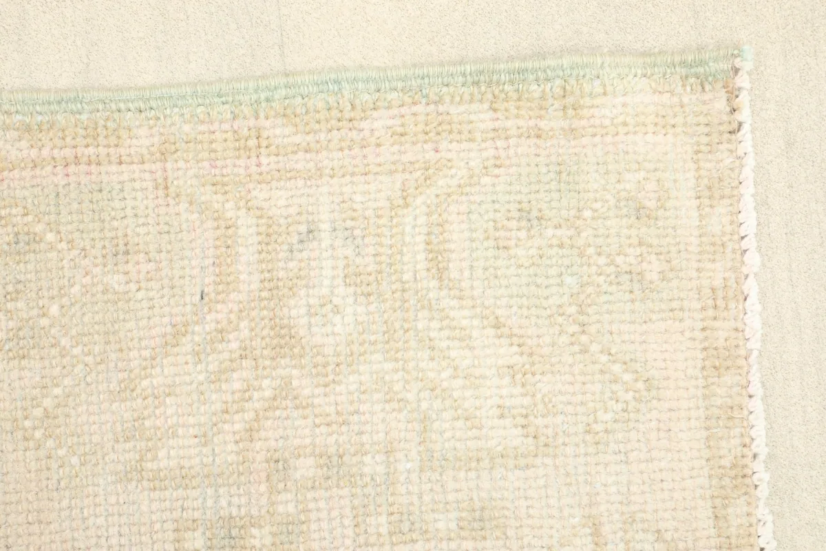 Detailed shot of the rug's edge, revealing the intricate hand-knotted construction and minor wear.