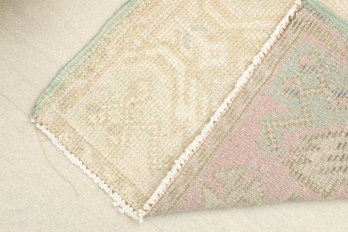 View of the rug's reverse side and a folded corner, showing the cotton foundation.