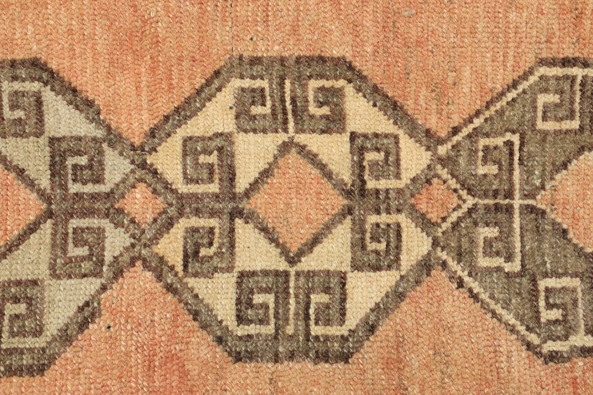 Tight detail of the interlocking gray and beige geometric motifs on the vintage rug.