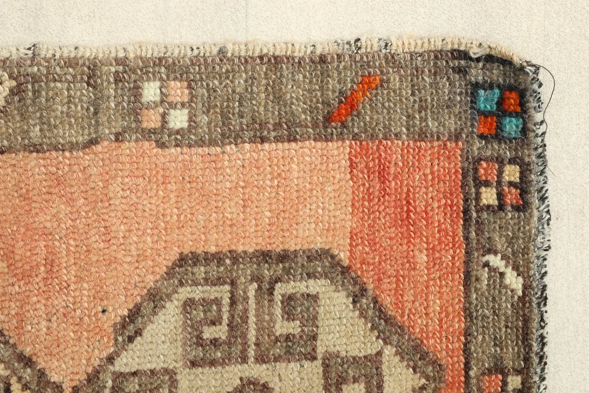 Close-up of a corner, highlighting the hand-knotted texture and minor wear on the border.