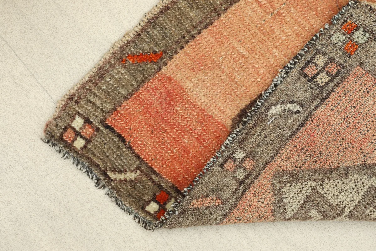 View of the rug folded, showing the thickness of the wool pile and details of the edges.