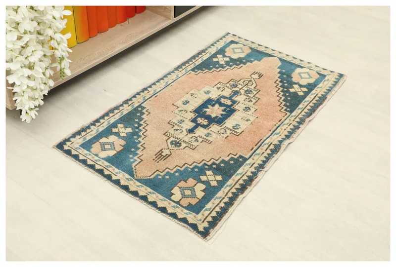 Full top view of the vintage rose and blue geometric rug on a white floor