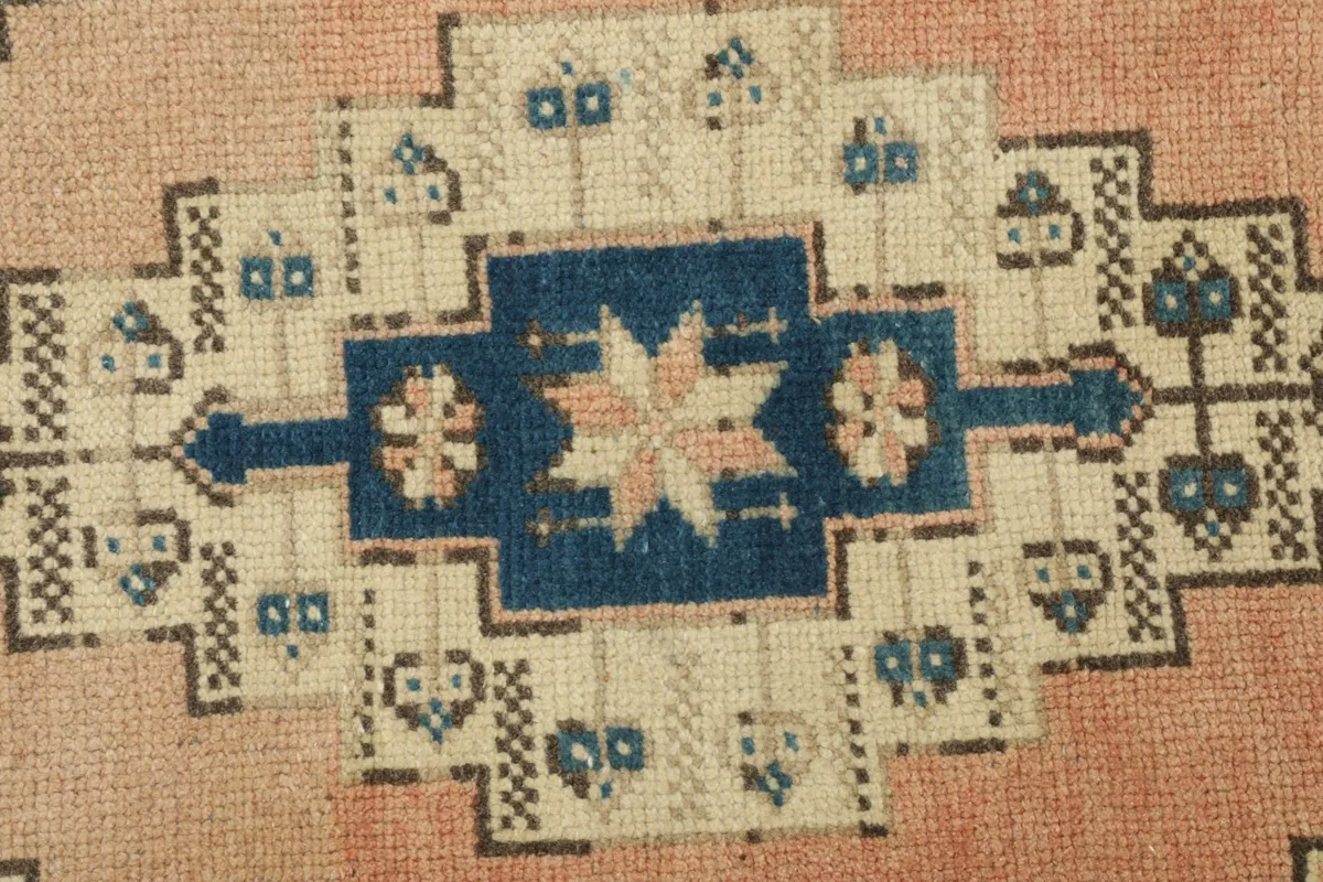 Close-up detail of the central medallion-like motif in blue, rose, and cream