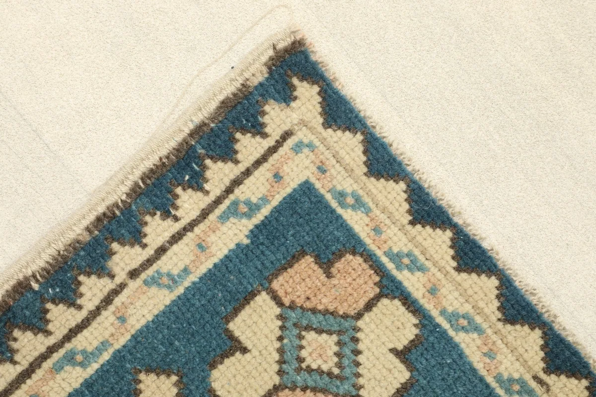 Corner detail of the rug showing the intricate geometric border pattern and colors
