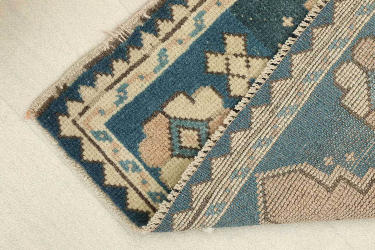 View showing the low pile and texture of the vintage wool rug as it folds