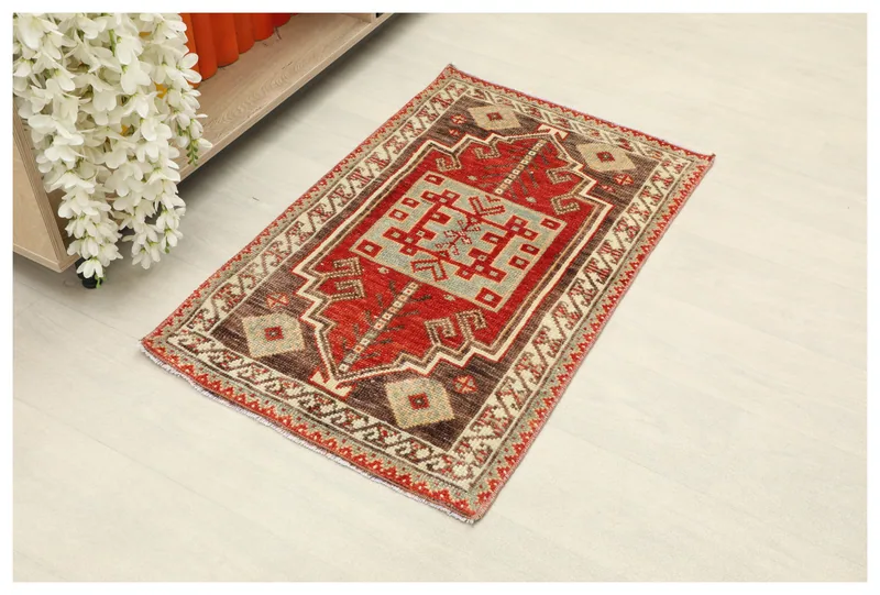 Full top view of a red, blue, brown, and beige vintage Anatolian geometric wool rug on a white floor.