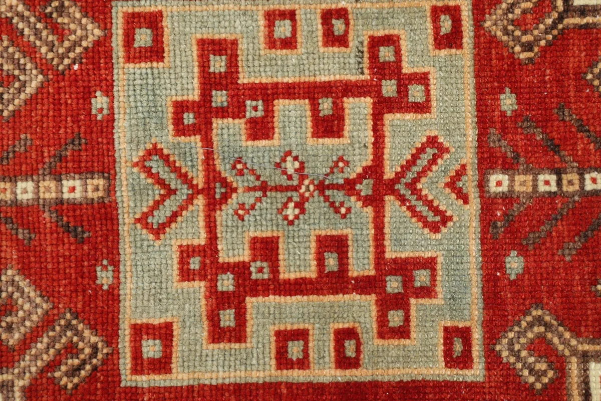 Detailed view of the intricate red and blue geometric patterns within the central medallion of the rug.