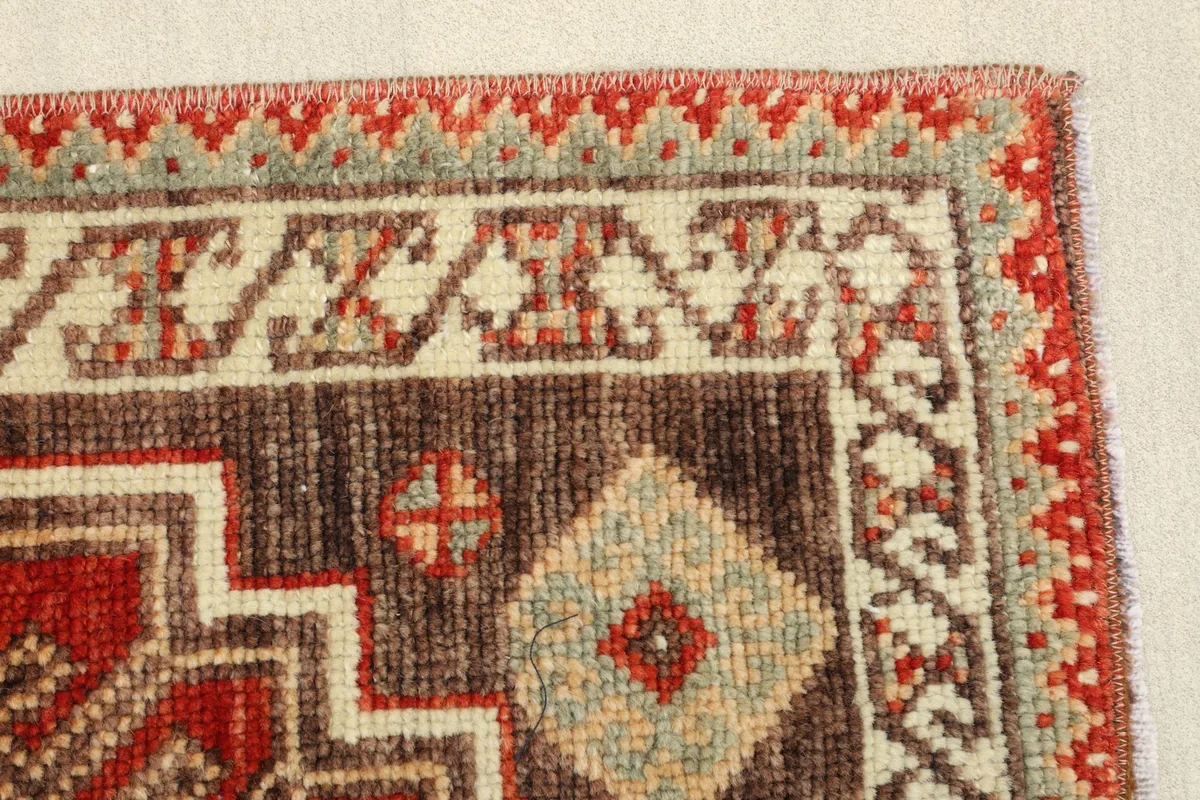 Detail of the border and field, showcasing the brown and beige patterns adjacent to the red main area.