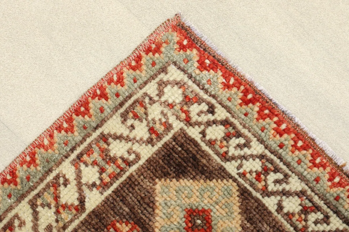 Close-up of the corner showing the layered borders in red, beige, and brown with geometric motifs.