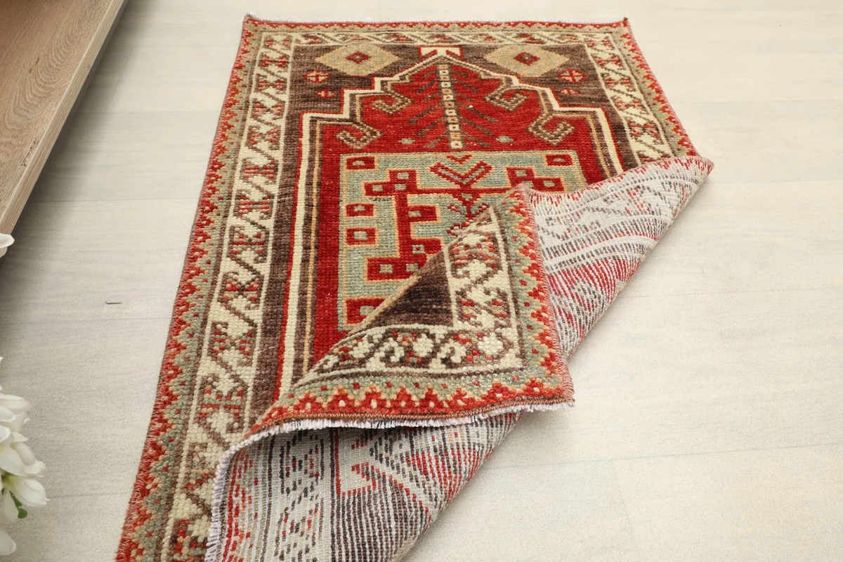 The rug partially folded, showing both the top design and the cotton foundation on the reverse side.